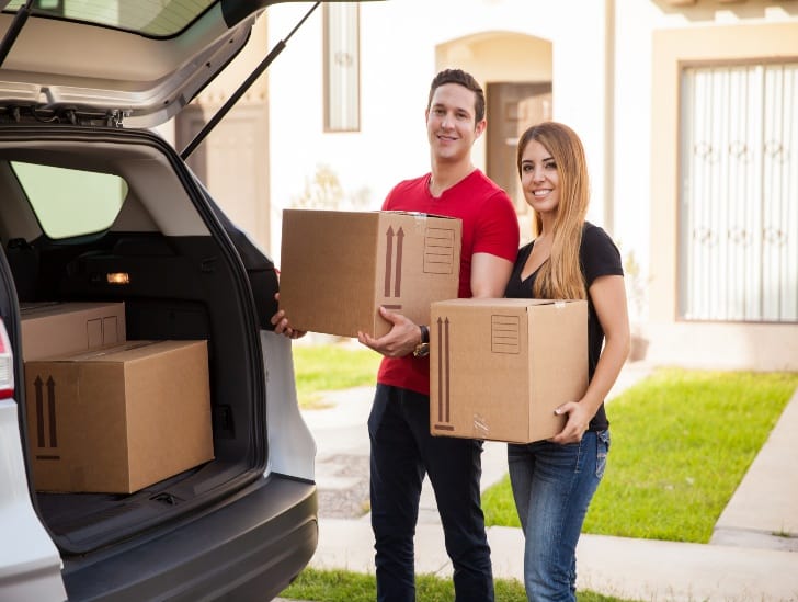 A couple loading moving boxes on the car.