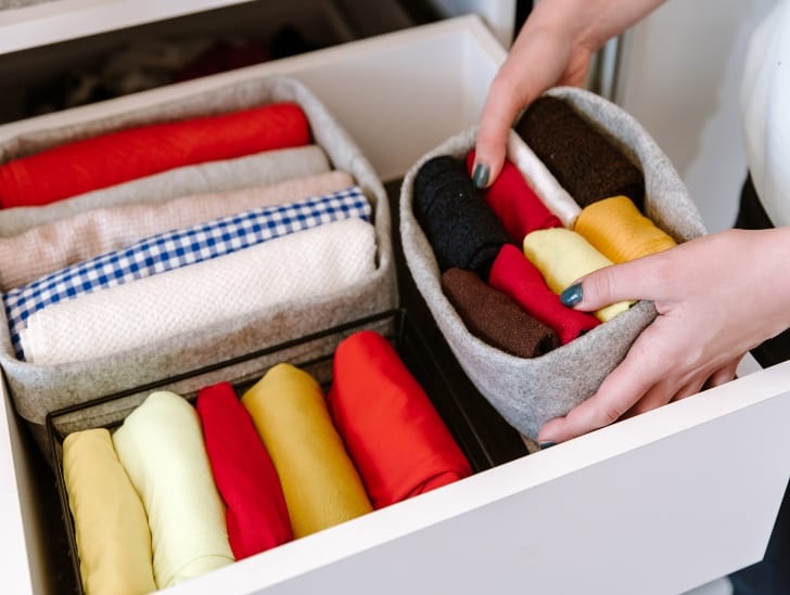 A woman organizing the clothes on the closet drawer.