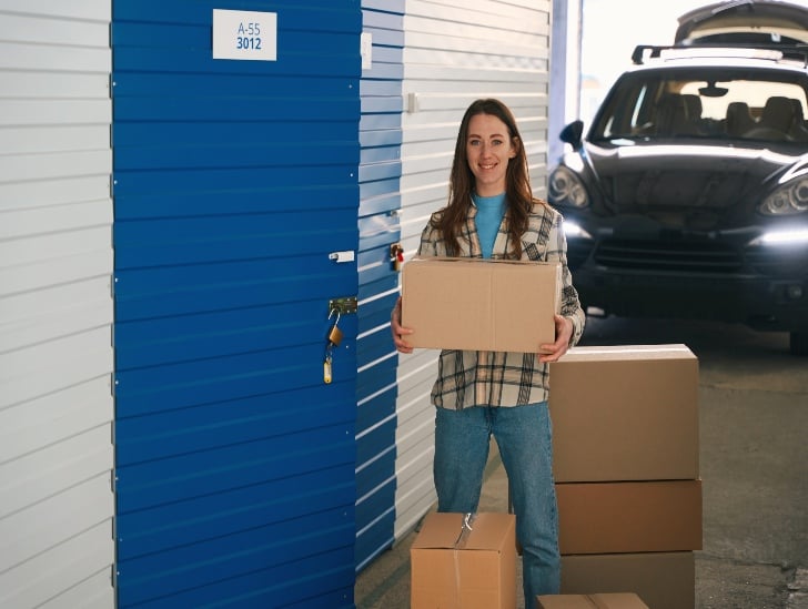 A woman loading the boxes on the self storage unit.